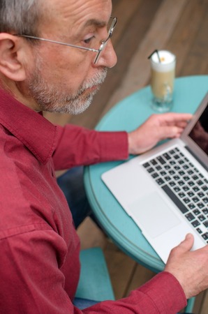 Aged man using his laptop on the table