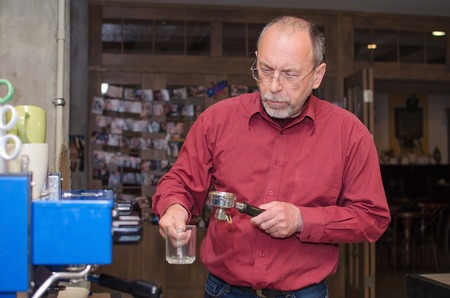 Aged man making coffee with coffee machineの写真素材