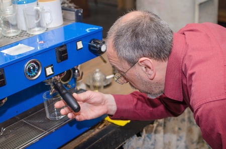 Aged man making coffee with coffee machine