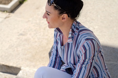 young girl sitting on the steps and resting in the shadowの写真素材