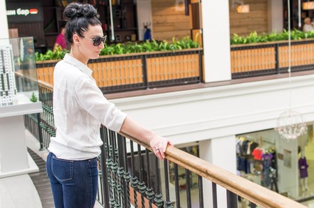 Young woman standing near the fence in the shopping mallの写真素材