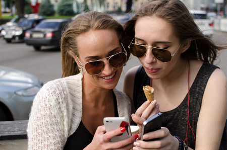 Two girlfriends are making selfie on the streetの写真素材