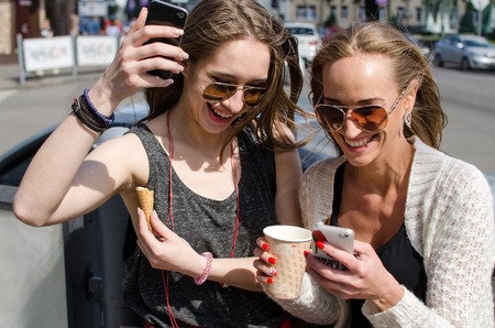 Two girlfriends are making selfie on the streetの写真素材