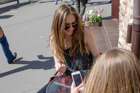 Two girlfriends are using cellphones in the cafeの写真素材