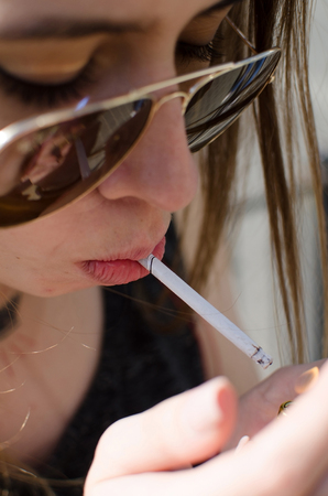Young woman is smoking on the street