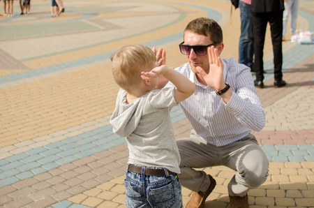 Small baby boy is having fun in the park with his father