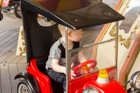 Little boy is riding the car and turning backの写真素材