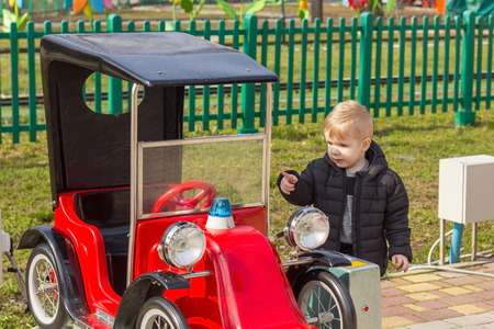 Little boy in black coat pointing the red car