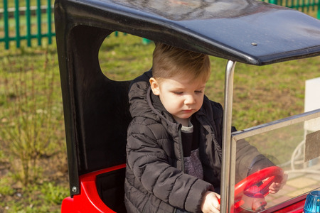Kid in black coat is riding red carの写真素材