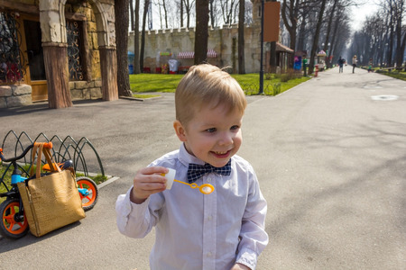 Small boy in shirt is playing with bubbles and laughing
