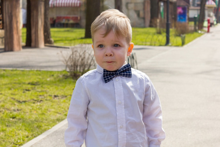 Cute blond child in shirt with bow tie in parkの写真素材