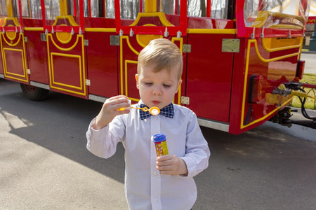 Cute little blond child in shirt with soap bubbles toyの写真素材