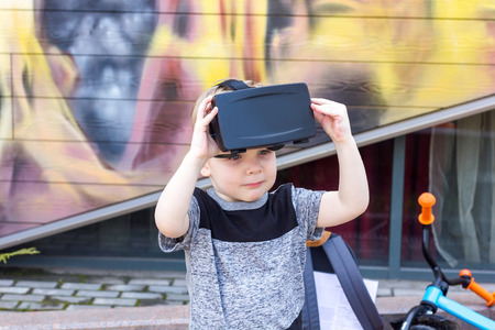 Boy in grey t-shirt is standing and holding the virtual glassesの写真素材