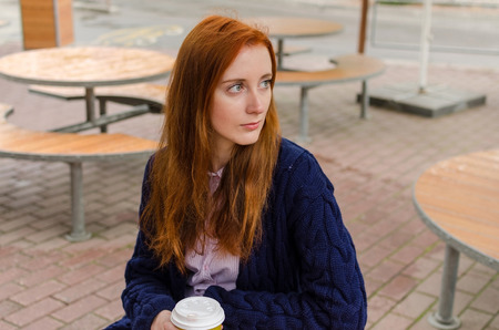 Young red woman with hot tasty coffeeの写真素材