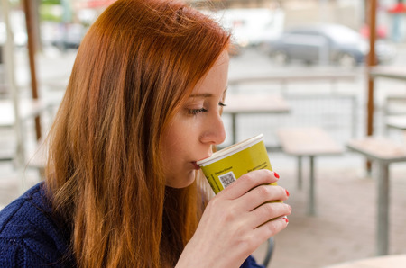 Young red woman with hot tasty coffeeの写真素材