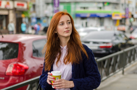 Young red woman with hot tasty coffee