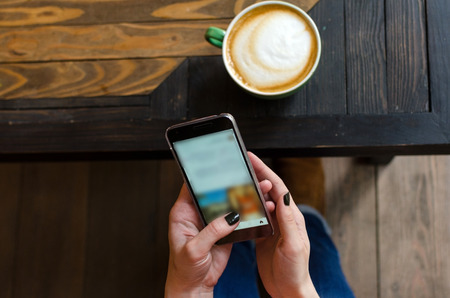 Young woman with a coffee and her cell phoneの写真素材