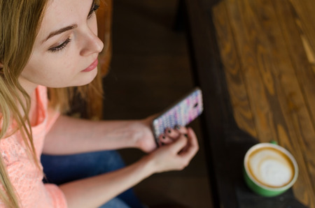 Young woman with a coffee and her cell phone