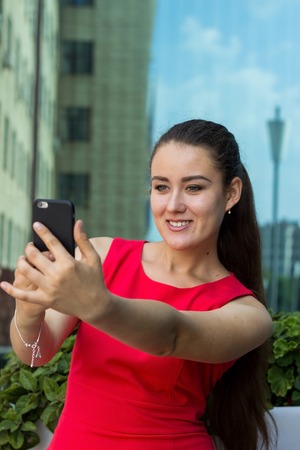 Young woman in der dress making selfie on the streetの写真素材
