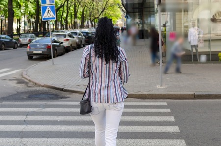 girl crossing the street on the empty crosswalkの写真素材