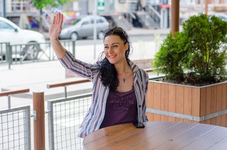 young girl sitting in the restaraunt and greeting peopleの写真素材