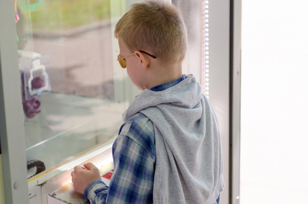 young boy playng claw machine in the parkの写真素材