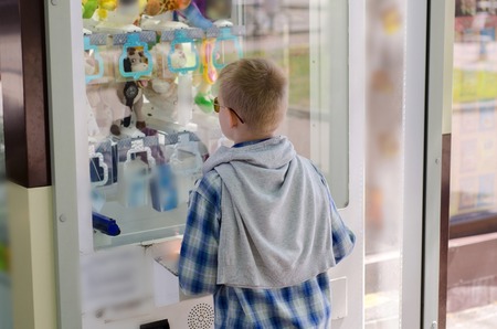 young boy playng claw machine in the parkの写真素材
