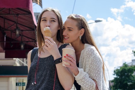 Two girlfriends are eating icecream and drinking coffee on the stretの写真素材