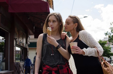 Two girlfriends are eating icecream and drinking coffee on the stretの写真素材