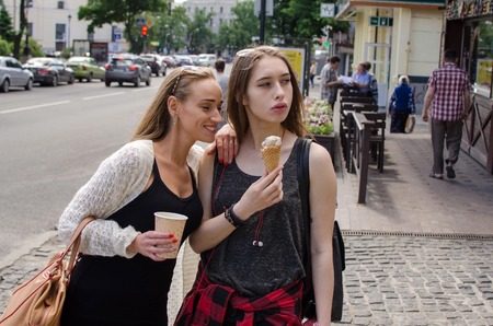 Two girlfriends are eating icecream and drinking coffee on the stretの写真素材