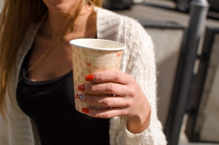 Young woman is drinking coffee on the streetの写真素材