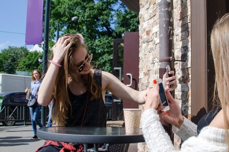 Two girlfriends are using cellphones in the cafeの写真素材