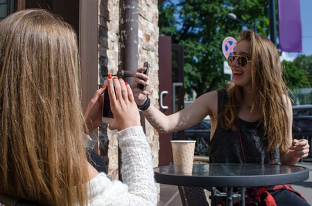 Two girlfriends are using cellphones in the cafeの写真素材