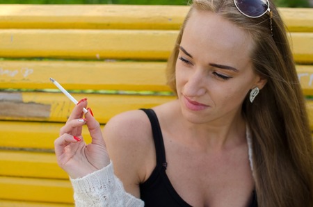 Young woman is smoking on the streetの写真素材