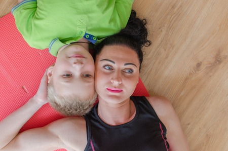 Young woman is making exercises with her sonの写真素材