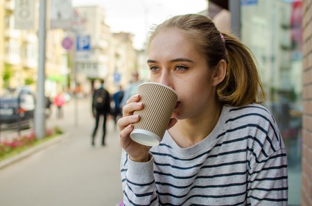 Young woman with tasty coffee on the streetの写真素材