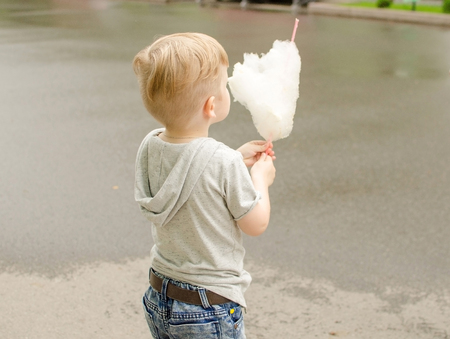 Small baby boy is eating cotton candy in the park
