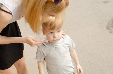 Young mother is taking care of her small son in the parkの写真素材