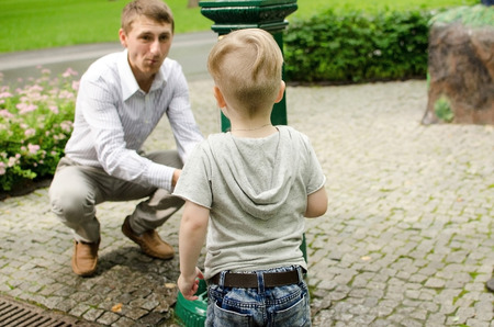 Small baby boy is washing hands with his father in the parkの写真素材
