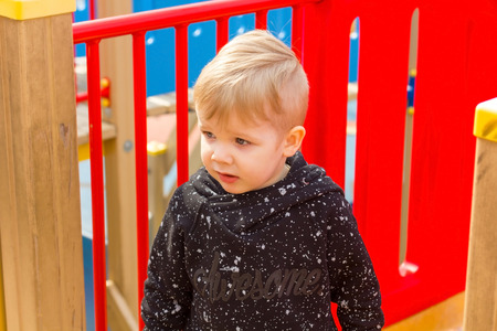Close-up photo of small boy near red fenceの写真素材