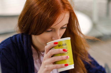 Young red woman with hot tasty coffeeの写真素材