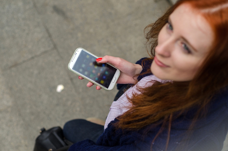 Young red woman using her cell phoneの写真素材