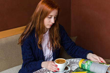 Young red woman with hot tasty coffeeの写真素材