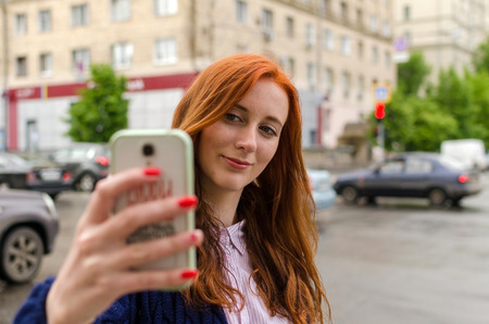 Young red woman making selfie with her cell phoneの写真素材