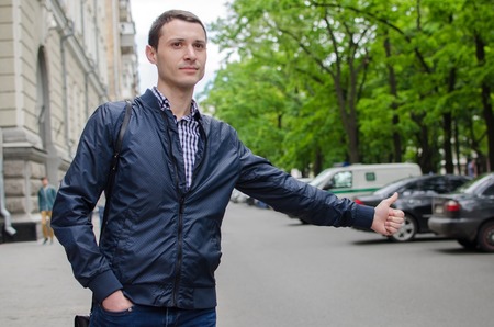 Young man is catching taxi on the streetの写真素材