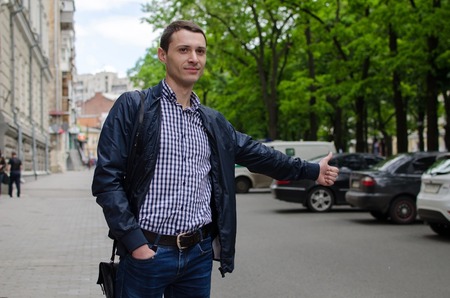 Young man is catching taxi on the streetの写真素材