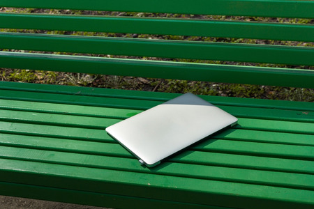 Closed laptop on the green bench