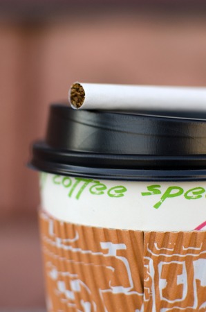 Cigarette next to plastic cup on the streetの写真素材