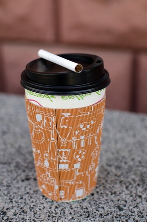 Cigarette next to plastic cup on the streetの写真素材