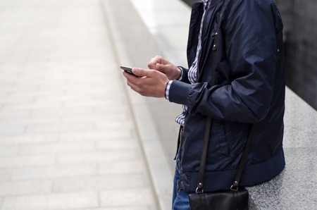 Young man using his phone on the streetの写真素材
